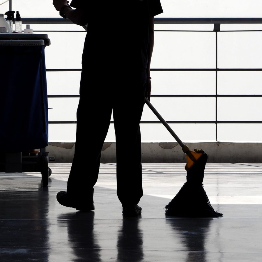 Silhouette image of cleaning service people sweeping the floor with a mop and other equipment on the trolley.